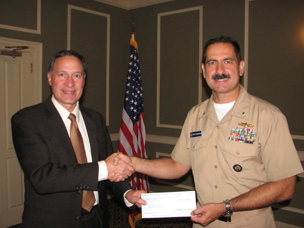 Frank Gallegos (l), senior manager, Omaha Office Corporate Business Development, Lockheed Martin, shakes hands with Cmdr. Paul Anderson, USN, chapter vice president of programs. At the September luncheon, Gallegos presented a check for $1,000 from Lockheed Martin to the chapter in support of its education fund.